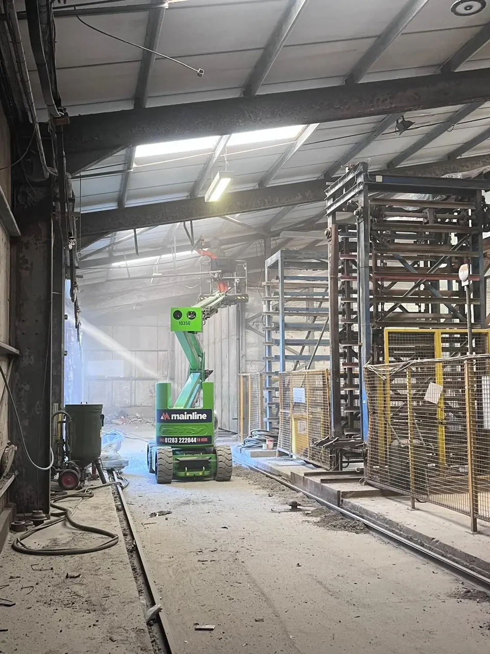 Inside the Belmont blast shop, with a cherry picker beside a tall steel frame being shot blasted