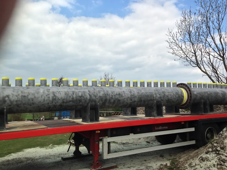 Long steel cold collectors for a power station, blasted and loaded on a trailer